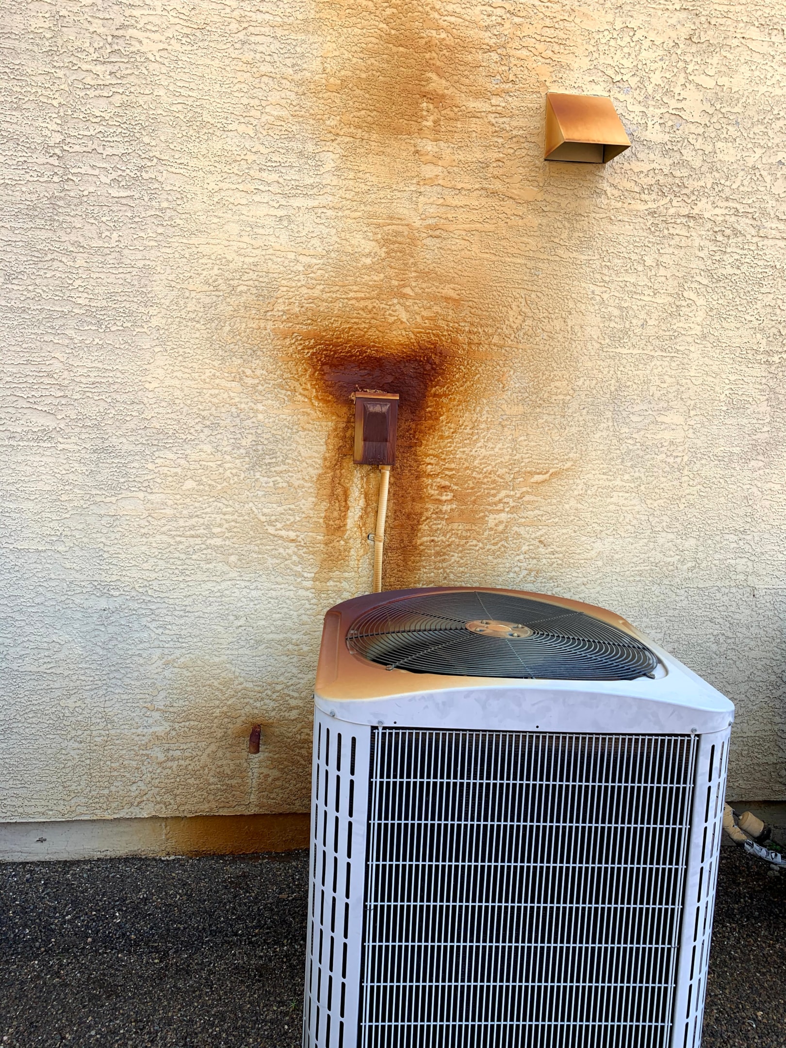 A technician inspecting an older air conditioning unit to determine if it should be replaced, focusing on its condition.